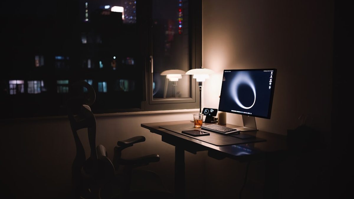 Desk with computer and lamp at night