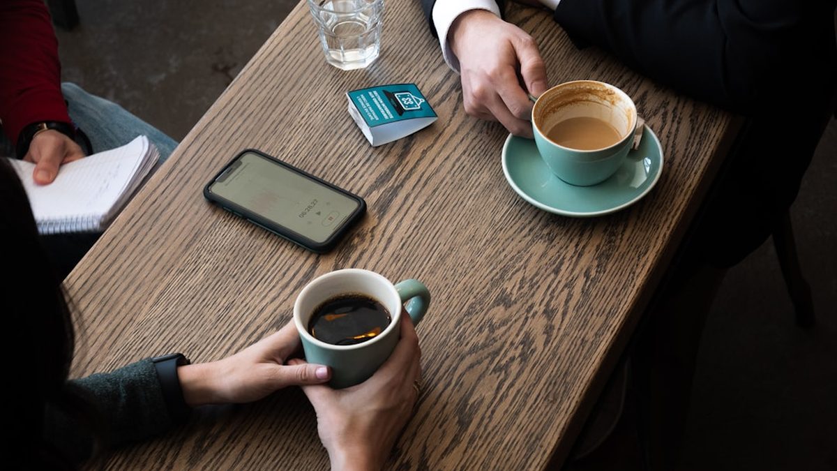 a couple of people sitting at a table with a cup of coffee