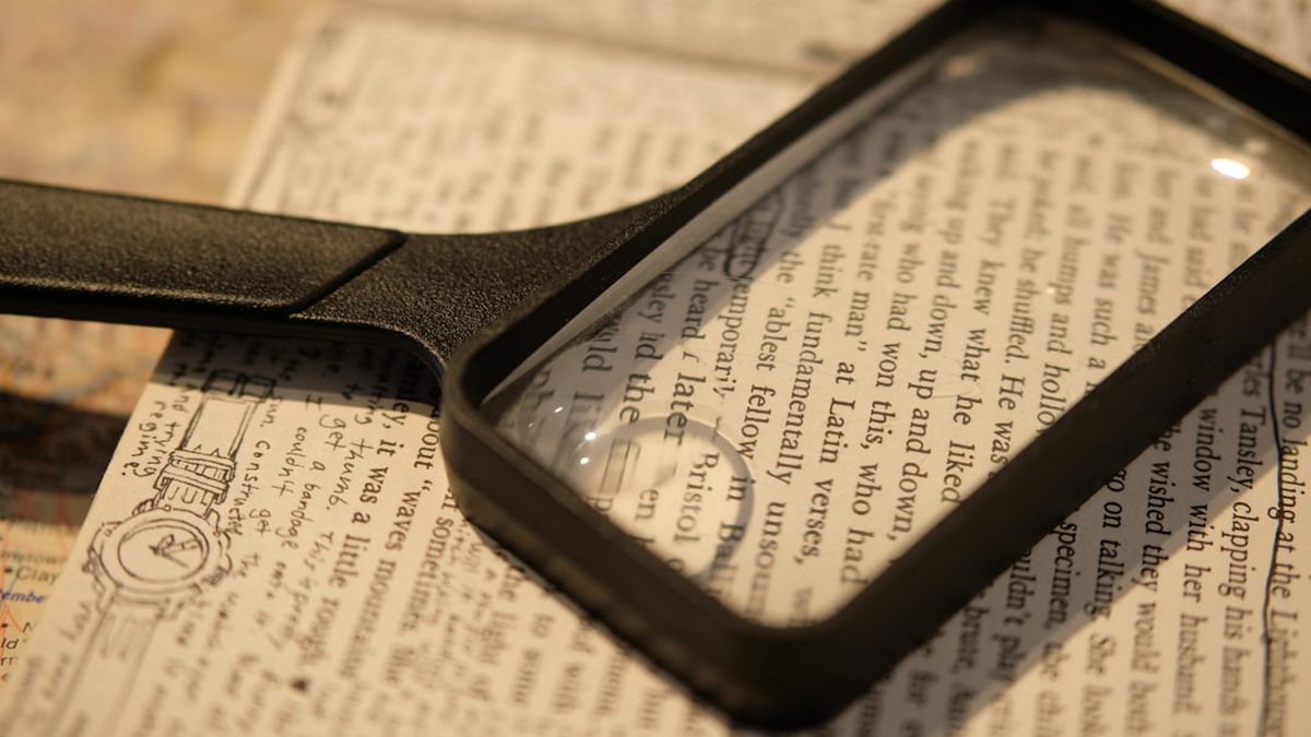 A black magnifying glass resting on a page of printed text