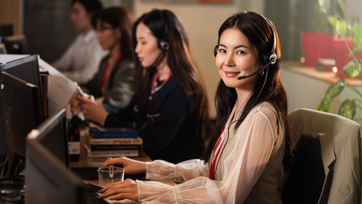 A smiling woman wearing a headset at a computer